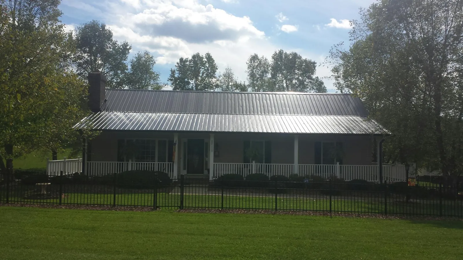 Gray metal roof on a brick ranch with a full width front porch — Gutter Guard Installation work by our crew in Callaway