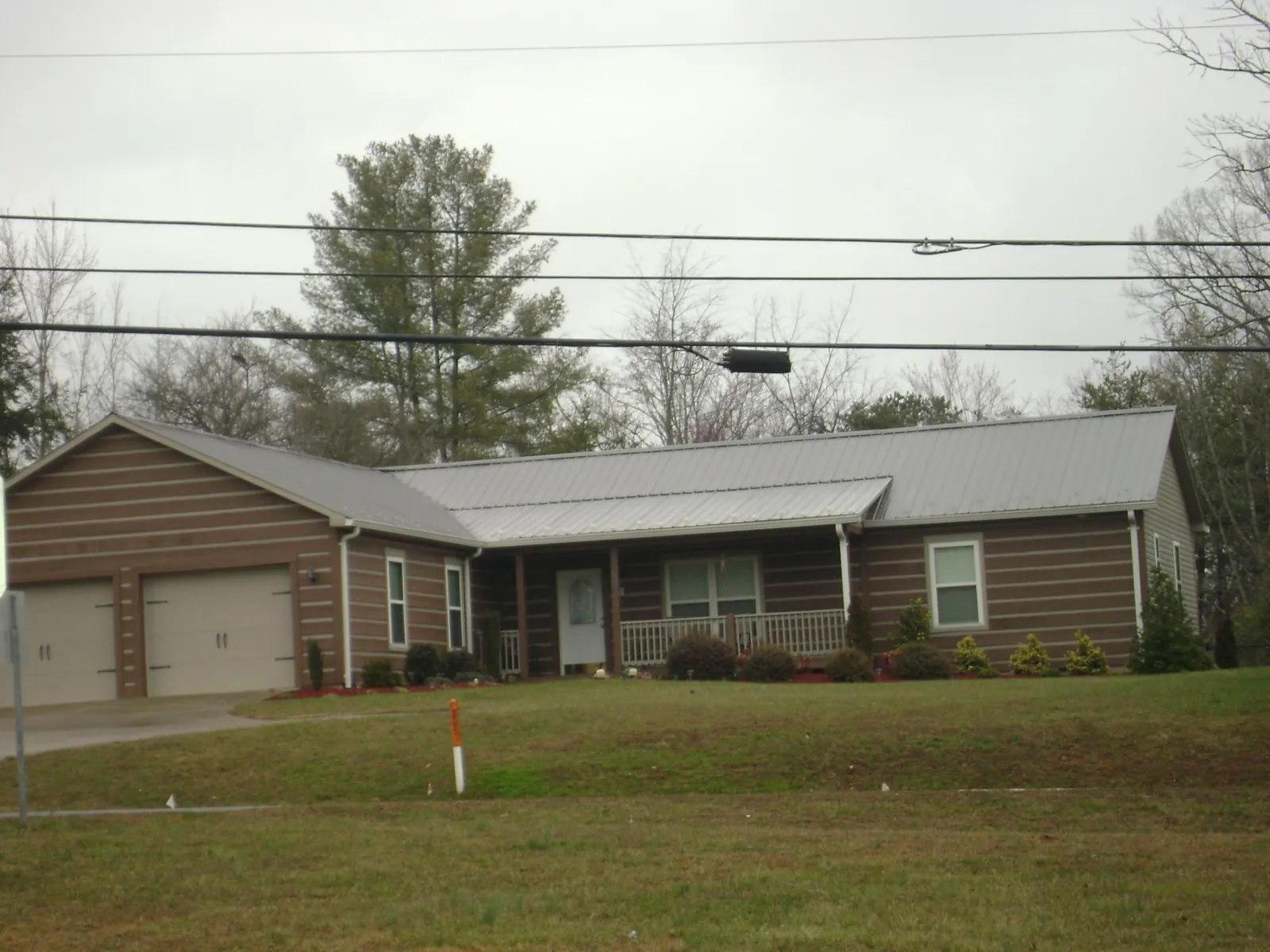 Gray metal roof on a log sided ranch home with a front porch in Callaway
