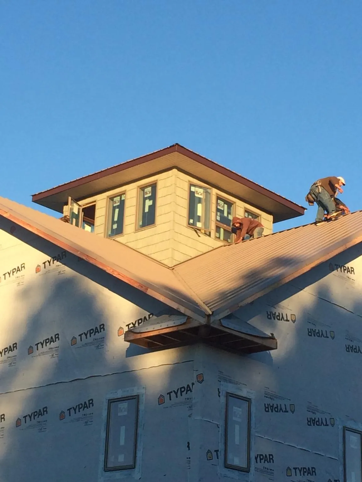 Roofers working around a rooftop cupola on a new metal roof at sunset — Roof Waterproofing in Callaway by Roofing Brothers